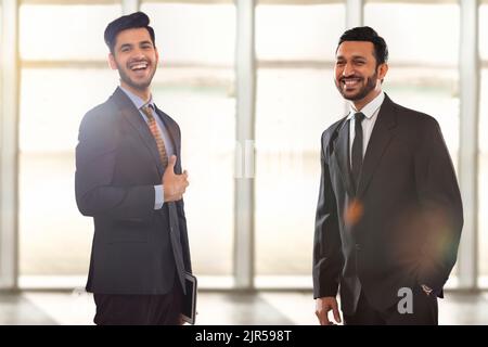 Firmenmitarbeiter in formellen Geschäftskleidung stehen im Büro und lächeln. Stockfoto