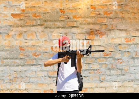 Bewaffneter junger Teenager, der mit einem Gewehr zielte Stockfoto