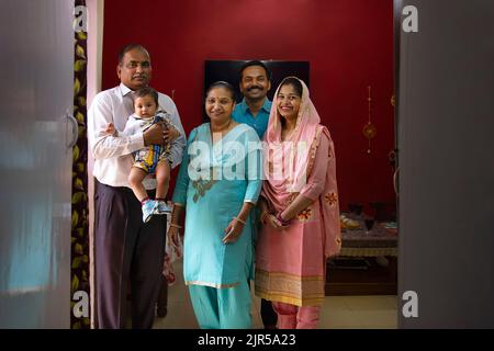 Porträt glücklicher indischer Familienmitglieder, die zu Hause zusammenstehen Stockfoto