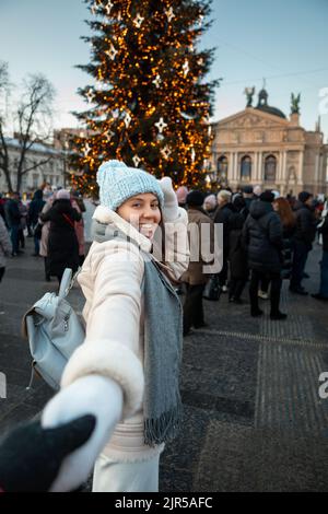 Folgen Sie mir Konzept Frau zieht Mann zum weihnachtsbaum Stockfoto