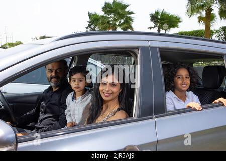 Porträt einer glücklichen indischen Familie in einem Auto Stockfoto