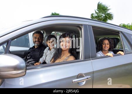 Porträt einer glücklichen indischen Familie in einem Auto Stockfoto