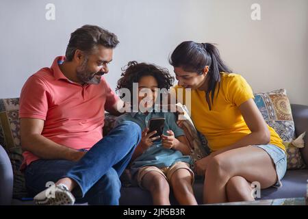 Familie beobachtet Smartphone und Spaß zusammen im Wohnzimmer Stockfoto