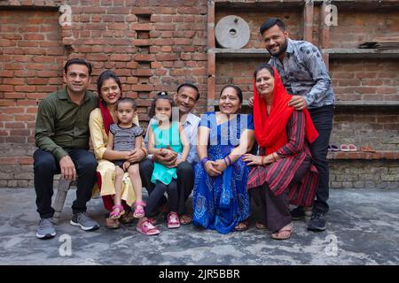 Porträt einer Familie aus der unteren Mittelschicht, die auf einem Kinderbett im Hinterhof sitzt Stockfoto