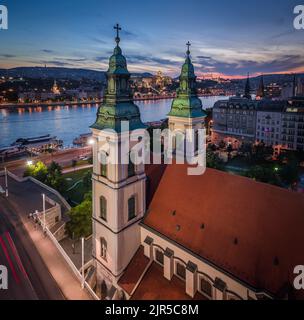 Budapest, Ungarn - Luftpanorama der beleuchteten Mutterkirche der Jungfrau Maria von der Himmelfahrt in Budapest und der Elisabethbrücke in der Abenddämmerung Stockfoto