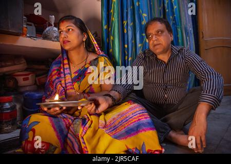 Indisches Paar mittleren Alters, das aarti zusammen mit dem Halten von diya zu Hause durchführt Stockfoto