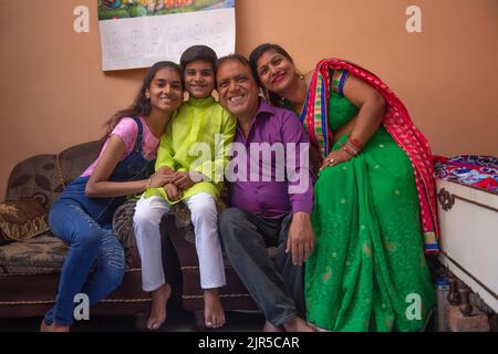 Porträt einer fröhlichen Familie, die zu Hause zusammen sitzt Stockfoto