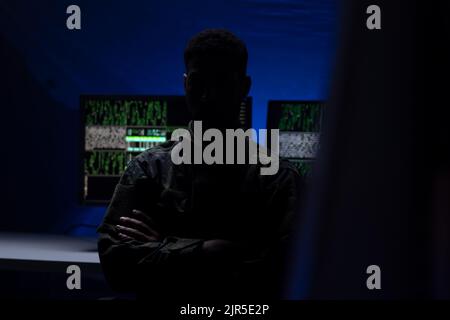 Anonymer Hacker in militärischer Uniform auf dunklem Web, Cyberwar-Konzept. Stockfoto