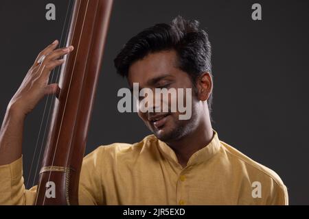 Nahaufnahme eines männlichen Musikers, der mit Tanpura beim Konzert auftrat Stockfoto