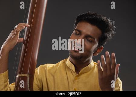 Nahaufnahme eines männlichen Musikers, der mit Tanpura beim Konzert auftrat Stockfoto