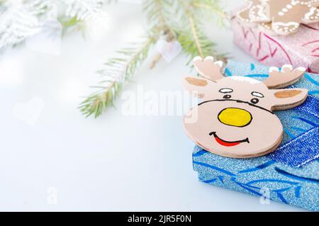 Niedliche Hirschfigur aus Sperrholz mit einem Weihnachtsbaum-Ast und einer glänzenden Schneeflocke. Weihnachtliche Inneneinrichtung, Weihnachtsdekor. Stockfoto