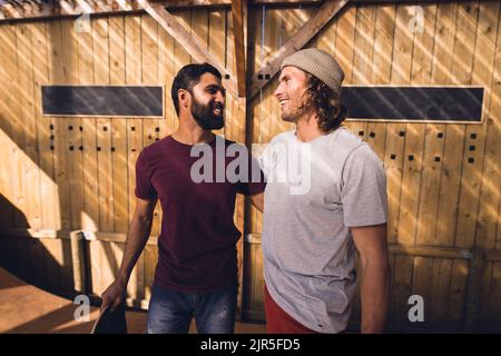 Bild von glücklichen, vielfältigen männlichen Freunden mit Skateboards im Skatepark Stockfoto