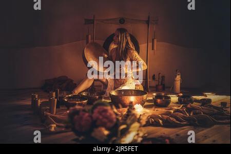 Schöne Frau spielt auf tibetischer Schale, zeremonieller Raum. Stockfoto