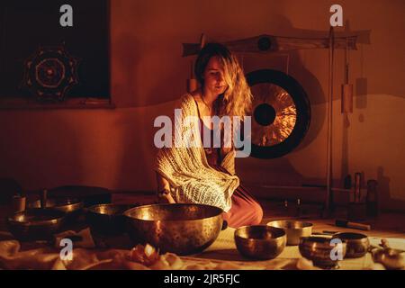 Schöne Frau spielt auf tibetischer Schale, zeremonieller Raum. Stockfoto