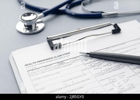Antragsformular für Krankenversicherung und Stethoskop auf dem Schreibtisch Stockfoto