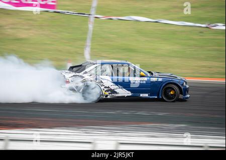 Ein weiß-blauer BMW E36, der Rauch auf einer Spur für einen Drift-Wettbewerb erzeugt Stockfoto