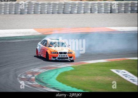 Ein orangefarbener BMW E46, der Rauch auf einer Spur für einen Driftwettbewerb erzeugt Stockfoto