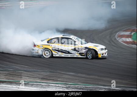 Ein weißgelber BMW E36, der Rauch auf einer Spur für einen Drift-Wettbewerb erzeugt Stockfoto