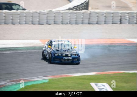 Ein weiß-blauer BMW E36, der Rauch auf einer Spur für einen Drift-Wettbewerb erzeugt Stockfoto