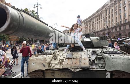 KIEW, UKRAINE - 20. August 2022: Kinder auf Panzern. Auf Chreschtschatyk in Kiew wird eine Ausstellung zerstörter russischer Ausrüstung organisiert Stockfoto