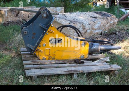 Ein großes Detail der Baumaschinen, ein Presshammer liegt auf einer Palette. Stockfoto