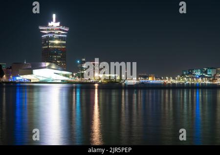 Skyline von Amsterdam bei Nacht, moderne Gebäude am IJ-Fluss Stockfoto