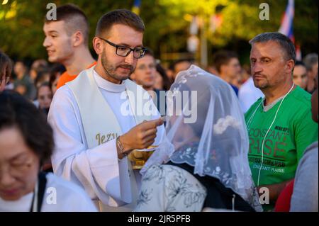 Ein Priester, der den Gläubigen die heilige Kommunion gibt. Stockfoto