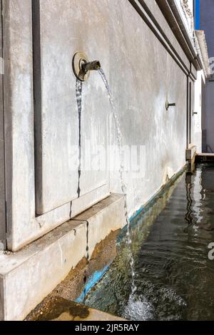 Brunnen mit Wasserauslauf, der aus der Wand kommt Stockfoto