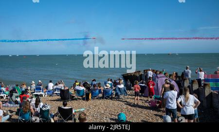 Zwei Flugzeuge des RAF Red Arrows-Kunstflugteams fliegen direkt aufeinander zu, während die Zuschauer am Strand der Eastbourne Airshow zusehen. Stockfoto