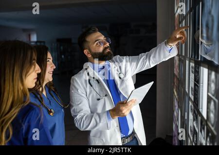 Eine Gruppe von Chirurgen-Praktikanten untersucht die fetale Entwicklung in verschiedenen Stadien der Schwangerschaft. Konzept der Gesundheitserziehung. Medizinstudenten im Klassenzimmer Stockfoto