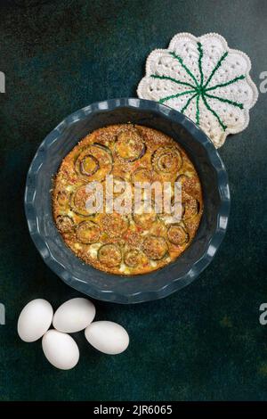 Hausgemachtes Zwiebelomelett in einem blauen Topf auf rohem dunklen Hintergrund. Stockfoto