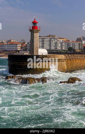 Wellen schlagen gegen die Basis des Leuchtturms Farol das Felgueiras in Foz do Douro in der Nähe von Porto im Norden Portugals. Stockfoto