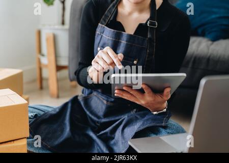 Startup-kmu-Unternehmer mit digitalem Tablet, der die Bestellung von Online-Bestellungen des Kunden überprüft. Stockfoto