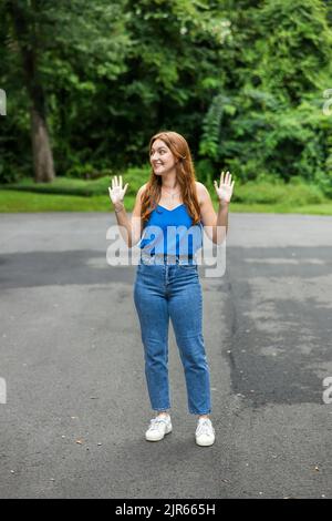 Ein hübsches, rothaariges Teenager-Mädchen, das ein blaues Tanktop trägt und Jeans, die sich auf den Weg zum College machen Stockfoto