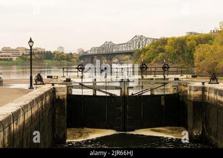 Rideau Kanal Rideau Waterway Herbst rote Blätter Landschaft. Herbstlaub in Ottawa, Ontario, Kanada. Alexandra Bridge im Hintergrund. Stockfoto