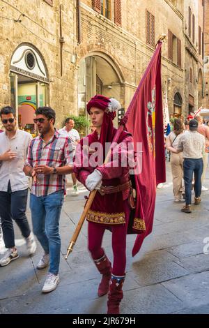 Mann in mittelalterlicher Tracht und mit Flagge einer der Contrada in der Via di Città in Siena, Toskana, Italien Stockfoto