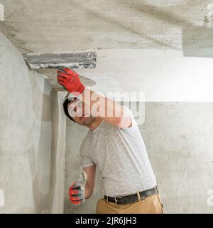 Kalkputz zum Nivellieren der Wände, der Meister führt Reparaturen im Raum durch, ebnen die Wände mit Betonmörtel. Stockfoto