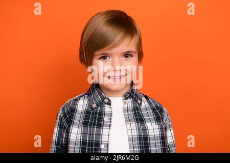 Foto von jungen fröhlichen kleinen Jungen toothy Lächeln tragen moderne Outfit isoliert über orange Farbe Hintergrund Stockfoto