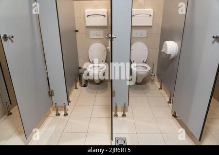 Reihe leerer Toilettenkabinen mit offener Tür in einer öffentlichen Toilette Stockfoto