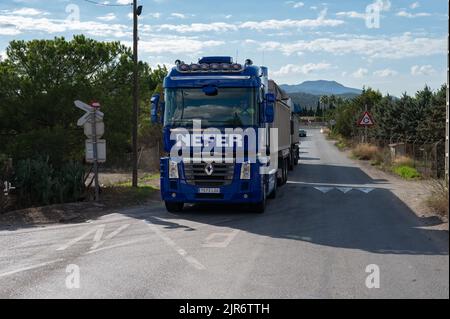 A big blue Renault Magnum truck with a trailer leaving the rural town in sunny weather Stock Photo