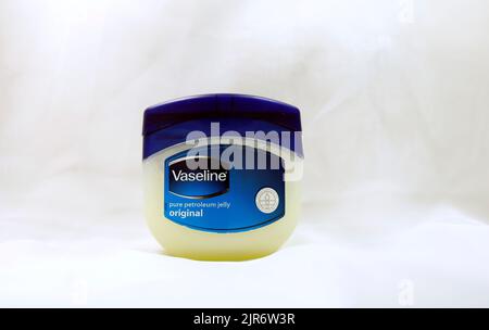 Vaseline in klarem Kunststoffglas mit blauem Deckel auf blau/grauem Hintergrund. Einrichtung von Studio. August 2022. Vaseline Original Petroleum Jelly Stockfoto