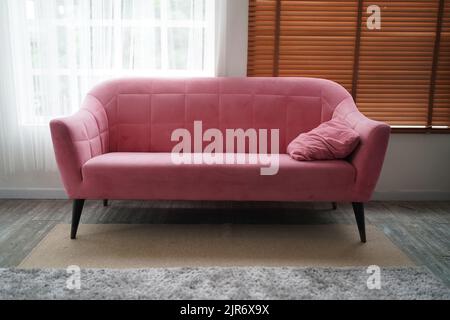 Modernes skandinavisches klassisches rosa Sofa mit Holzbeinen und Kissen isoliert auf weißem Hintergrund. Möbel, Inneneinrichtung, stilvolles Sofa. Rosafarbene Interi Stockfoto