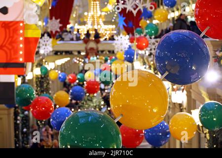 Weihnachtsschmuck im Einkaufszentrum. Unschärfer Blick auf festliche Lichter und Menschen, die zu Fuß gehen Stockfoto