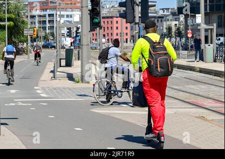 Antwerpen, Belgien - 2022. August: Person, die auf einem Elektroroller auf einer Fahrradspur entlang einer Straße im Stadtzentrum fährt Stockfoto