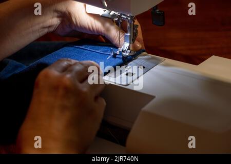 Weibliche Hände eines Schneidermeisters, der mit Denim-blauer Webart arbeitet Stockfoto