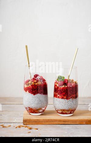 Zwei Gläser Chia Pudding mit Müsli und Himbeeren. Stockfoto