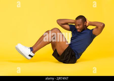 Black Fitness Guy Tut Sit-Ups Übung Auf Gelbem Hintergrund Stockfoto