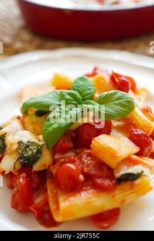 Italienische Paccheri-Pasta mit Kirschtomatensoße, Mozzarella-Käse und frischem Basilikum Stockfoto