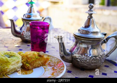 Minztee im marokkanischen Stil und Nahost-Süßigkeiten auf der Terrasse der El Bañuelo Teteria in Granada, Spanien Stockfoto