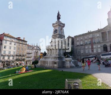 Statue von Prinz Heinrich dem Navigator außerhalb des Bolsa-Palastes in Porto Portugal an einem Sommertag, an dem die Menschen auf dem Rasen sitzen. Stockfoto